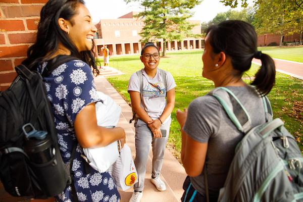 Three female students talking outside a building